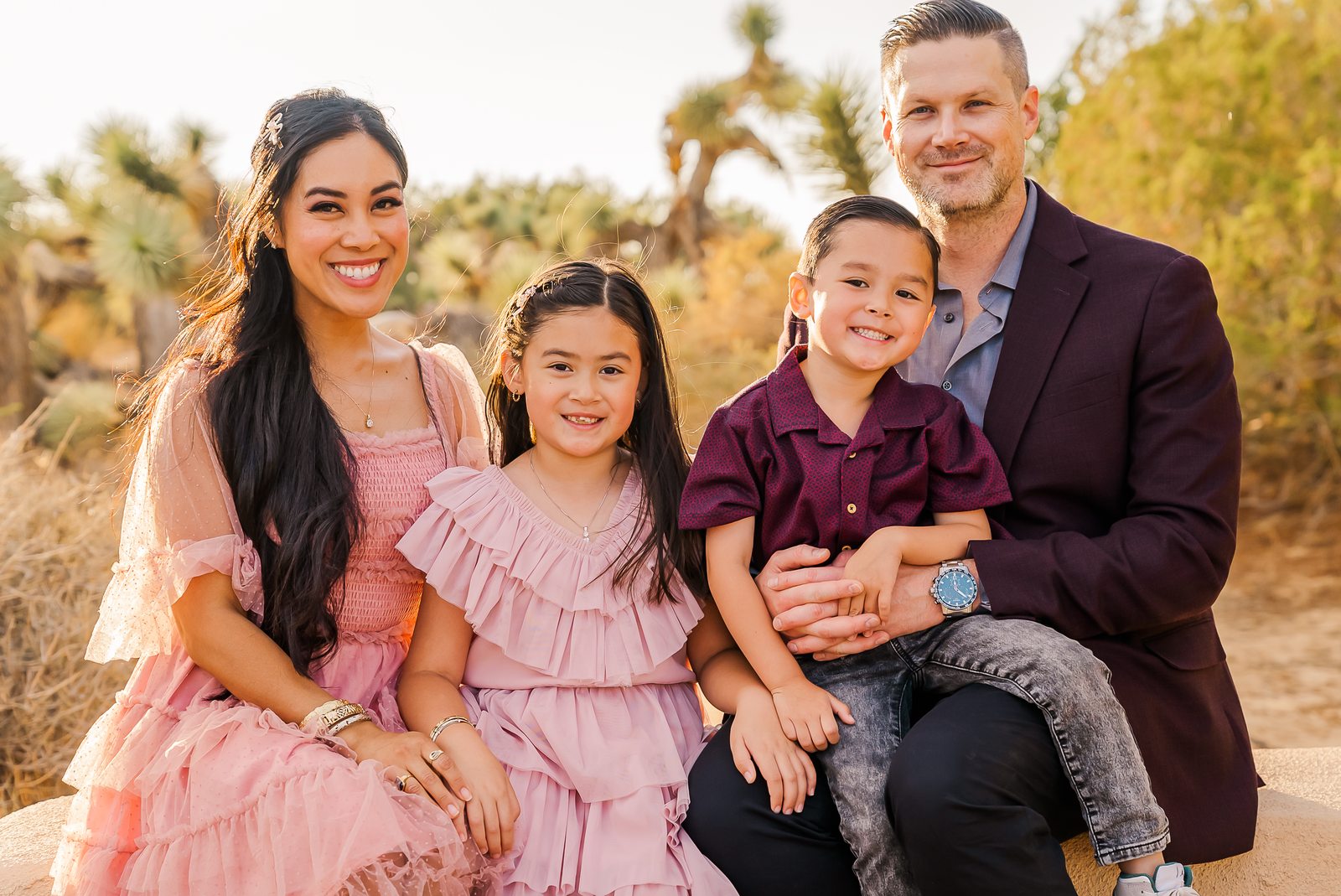 A family of four seated together at golden hour among Joshua trees