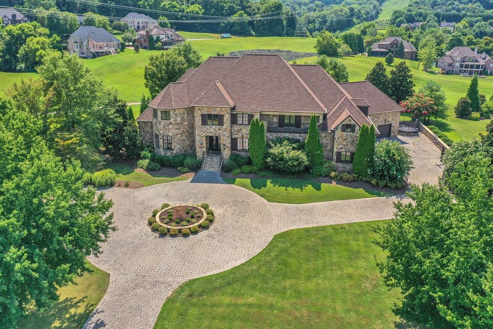 Aerial view of a stone home with a circular paver driveway